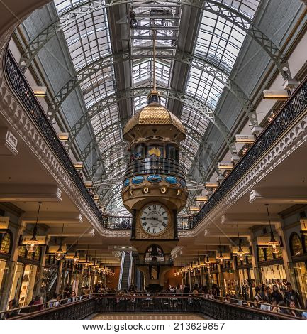 Sydney Australia - March 25 2017: Elaborate mechanical date-system and clock work hanging from ceiling inside historic Victoria Shopping Mall. Metal bows and glass ceiling. People walking the balconies in front of shops.
