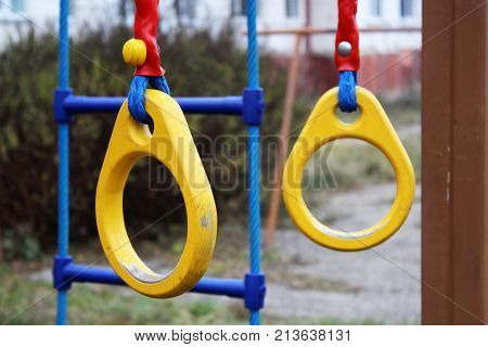 Traditional wooden gymnast rings hanging outdoor yellow color