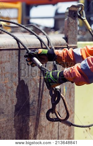 Hard job of able seaman on offshore vessel. He is connecting sling. Crane loading operations on deck of offshore  platform supply PSV vessel.  Hes is wearing safety gloves and coverall.
