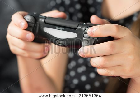 UFA RUSSIA - NOVEMBER 12 2017: Hand girl playing Sony Dualshock 4 controller for PlayStation 4 pro. Sony PlayStation 4 pro game console of the eighth generation.