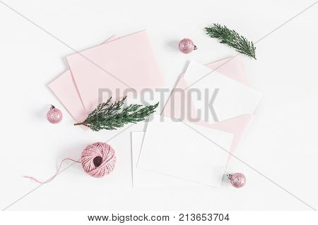 Christmas composition. Envelopes christmas pink decorations cypress branches on white background.  
