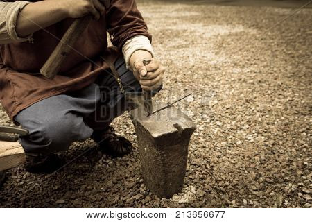 Work hammer on the anvil . In the park in nature