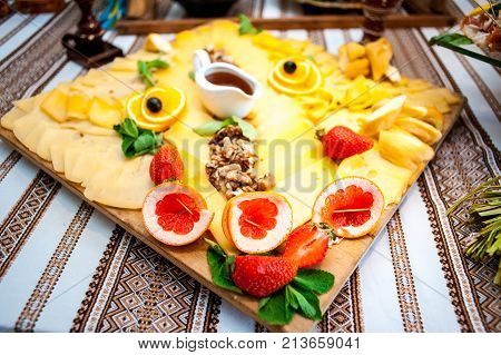 Fresh fruits and berries of different bright colors cut in small pieces are served on a table