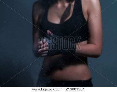 Young fighter boxer fit girl wearing hand bandage preparing before training. She has magnesia in hands