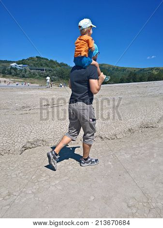 Man carrying his child on shoulders in an arid landscape