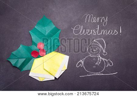 Chalk Merry Christmas text with origami bells on a black board school background