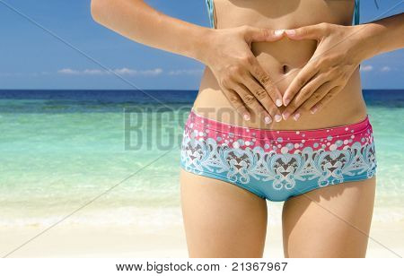 Mani di una donna che formano un simbolo del cuore sulla pancia