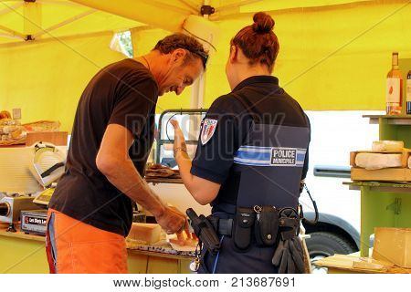 Valras-plage, Herault, France - Aug 25 2017: Female French Police Officer Buying Cheese From A Marke