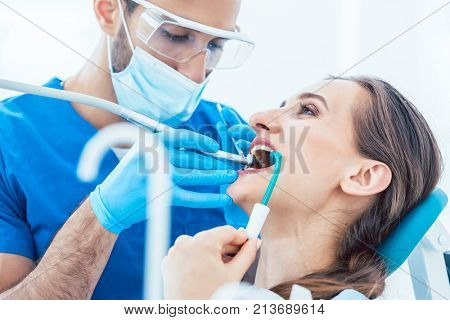 Side view close-up of a relaxed young woman during painless oral treatment in the modern dental office of an experienced and dedicated dentist
