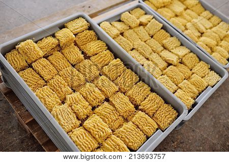 factory for the production of instant noodles. A lot of noodles in iron yags at the background of production.