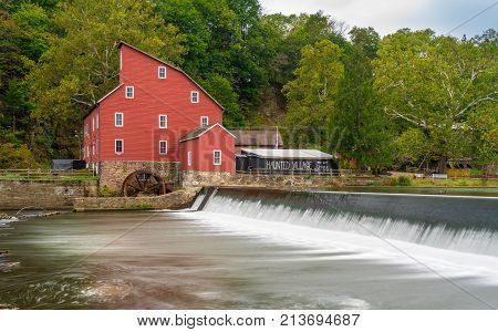 The historic Red Mill in Clinton NJ with people fishing in the river. The village also decorated for halloween as photo taken in Mid October