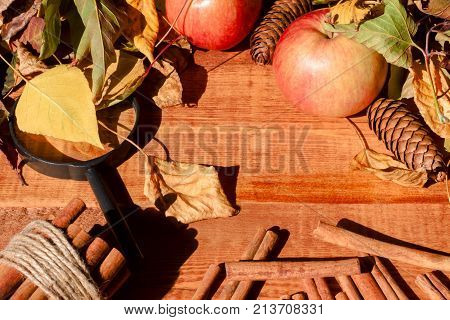 Ripe apples with cinnamon sticks on wooden table, on wooden background