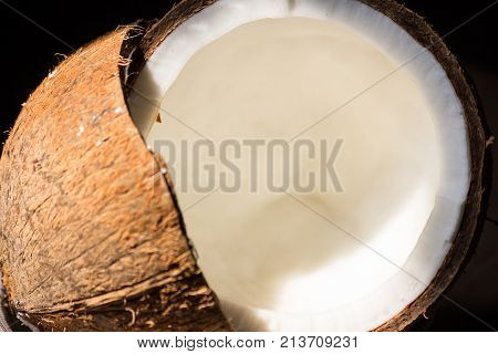 coconuts isolated on the black background Ripe half cut coconut on a wooden background. Ripe half cut coconut on a wooden background. Coconut cream and oil close up of a coconut on a wooden background