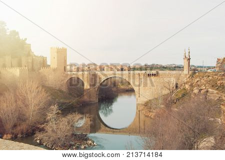 An Arch Alcantara Bridge Over The Tagus River And Its Reflection In Water On Winter Evening Day, Tol