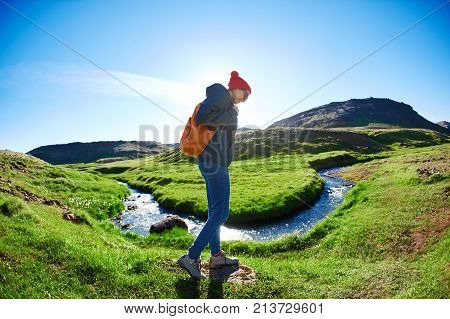 woman traveler with small orange backpack on a walk in the Valley of the river of Hveragerdi Iceland. Hiking Tour of Reykjadalur Hot Springs