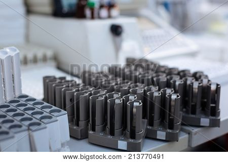 Fill me. Empty  silver  stands for test tubes placed on the edge of the table while surrounded by medical staff  looking technologically