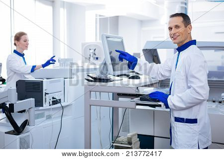 Medical discovery.  Budding genius reliable laboratorians analyzing the samples  wearing  lab coat while guy smiling at the camera