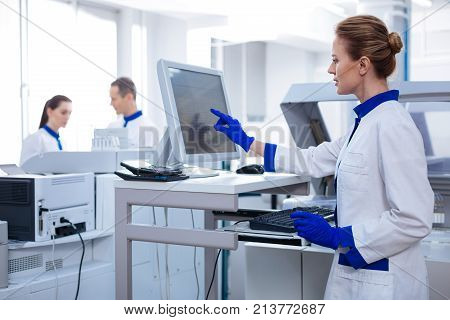 Science for women.  Blond beautiful female researcher filling medical chart while looking at the screen and  standing in the lab
