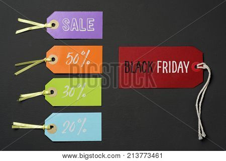 text black friday in a red paper label and some other paper labels of different colors with different percentages of discount, against a dark gray background