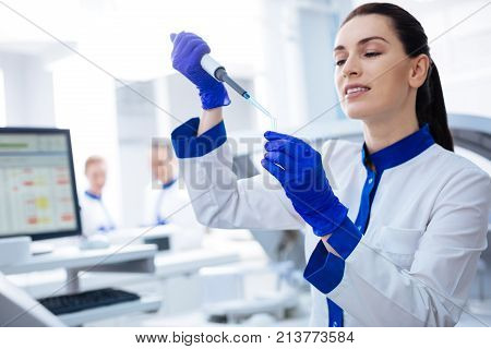 Perfect choice.  Inspired beautiful female intern holding vial looking at it attentively while posing in the lab