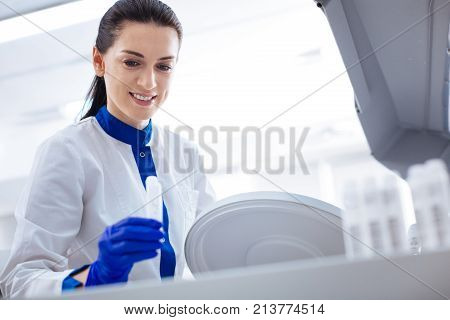 How it works. Pretty pleasant young  female scientist preparing for getting tests while carrying container and looking down