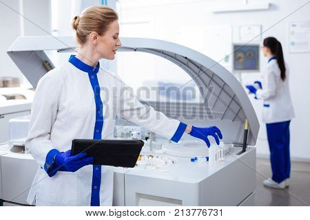 Here we go.  Intelligent genuine female scientist putting glassware according to the list written in the tablet which placed in the hand