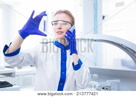 Wonderful news. Cheerful optimistic  sharing observation by phone while wearing labcoat and standing in the lab