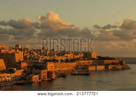 malta valletta . capital at sunrise with golden sky, clouds , harbor and boats. Old historical city