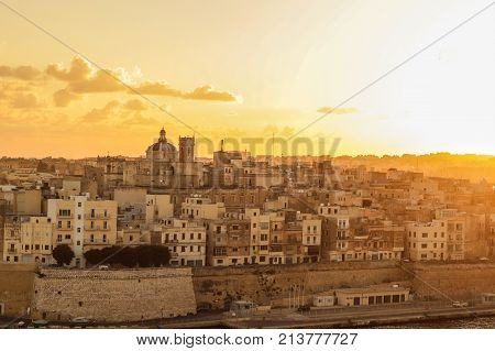 malta valletta . capital at sunrise with golden sky, clouds , harbor and boats. Old historical city
