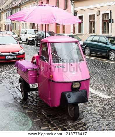 Sibiu Romania October 07 2017 : Pink scooter with closed cockpit and umbrella parked on the Timotei Popovich street in Sibiu city in Romania