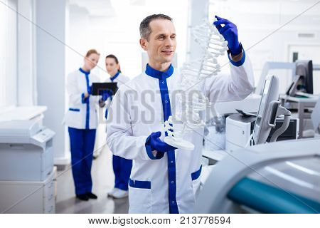 DNA mystery. Wistful happy male scientist carrying DNA and looking for gene  location while posing in the laboratory