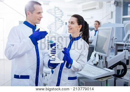 Abnormal DNA.   Pleased genuine Mal and female laboratory assistants want to find out mutation while  looking at each other and beaming