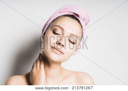 attractive young girl with clean skin and with a pink towel on her head poses