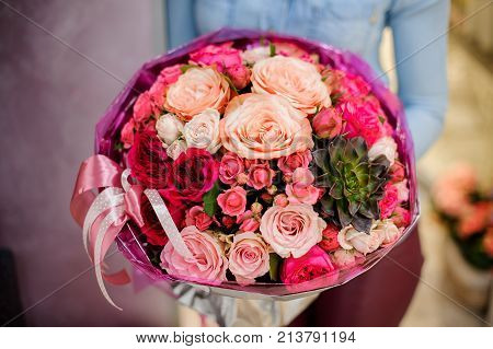Large and gorgeous pink bouquet of flowers in womans hands on the blurred background. Bouquet concept