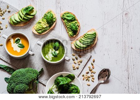 Vegetarian healthy food. Soup and vegan sandwiches. Different sandwiches with avocado. Brunch on white wooden background.