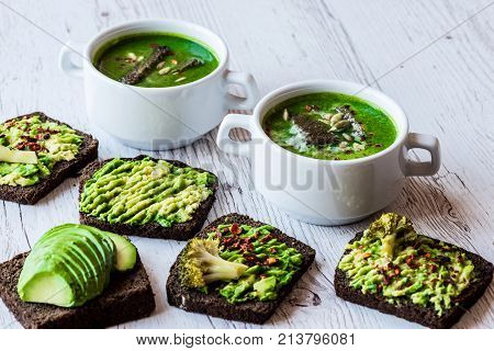 Vegetarian healthy food. Soup and vegan sandwiches. Different sandwiches with avocado. Brunch on white wooden background.