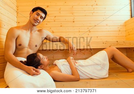 Couple at sauna spa healthy concept Young asian man handsome and woman beautiful together sitting in room with hot warm steam happy relaxing resting for health care and skin in holiday