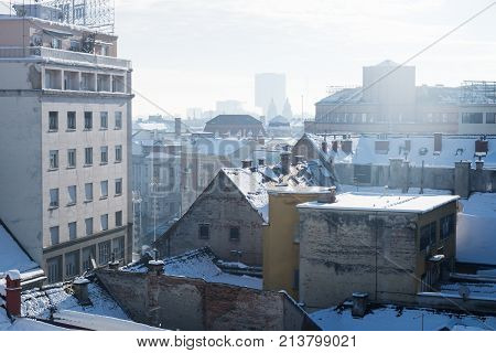 Panorama view over Zagreb with smoking chimneys during winter with snow over the roofs during sunny weather, Zagreb, Croatia, Europe