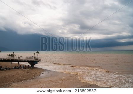 Heavy storm clouds approaching the beach, brown runoff water from a river turning the ocean bown