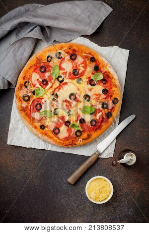 Pizza margarita with tomatoes mazarella and slices of olives on a dark concrete or stone background. Traditional Italian cuisine. Selective focus. Top view.