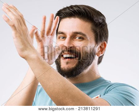 Portrait of cheerful teasing bearded man on grey background