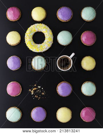 bright round desserts on a black background and a cup of coffee