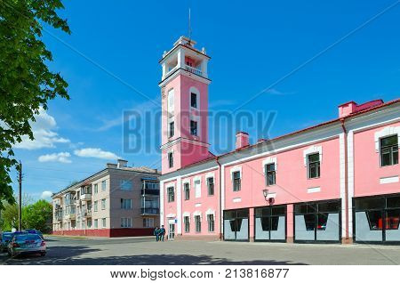 POLOTSK BELARUS - MAY 19 2017: Unknown employees of Ministry of Emergency Situations are walking along street near building of fire tower (built in 1927 now in building is still fire department) Belarus