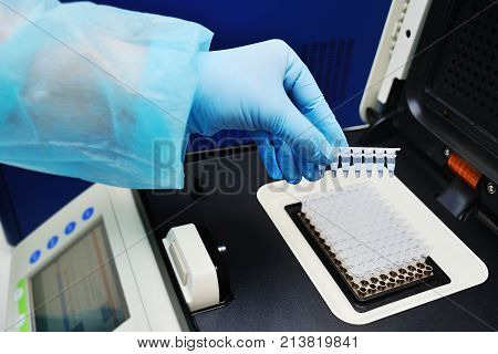Thermocycler for DNA and PCR tests and analyzes against the backdrop of a medical laboratory.Scientist putting small tube to machine in laboratory