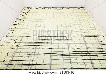 Electric floor heating system installation in new house electric heating cable is installed on the reinforcement grid with the help of mounting tape on the plates of expanded polystyrene