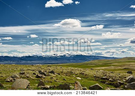 Travel to Iceland. road and river in a bright sunny mountain landscape. Vatna volcano covered with snow and ice on tne background.