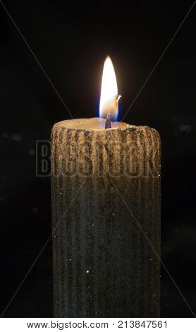 Christmas yellow candle on the black background.