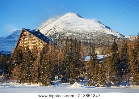 Winter view of the Strbske pleso village with hotel coniferous forest and snowy peaks. The village is a favorite ski tourist and health resort in the slovakian part of High Tatras mountains.