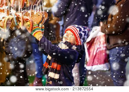 Little cute kid boy buying sweets from a cancy stand on Christmas market. Happy child on traditional family market in Germany. Preschooler in colorful winter clothes.