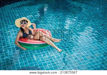 Women wearing bikini or swimware suits swimming pool sitting on a blue protrude at the resort town of Pattaya in Thailand.